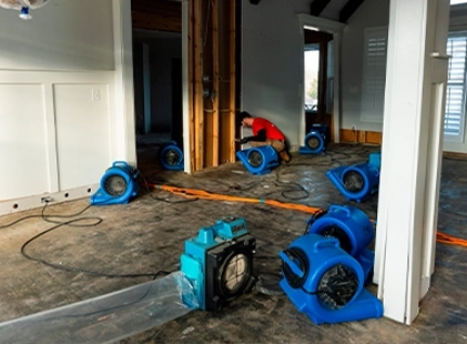 Water damage restoration professionals using drying equipment to dry floors and prevent further water damage in a home.